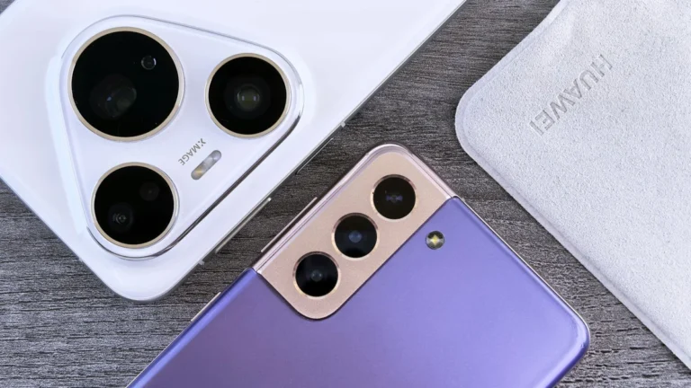 Close-up of two smartphones with camera focus on a textured wooden surface.