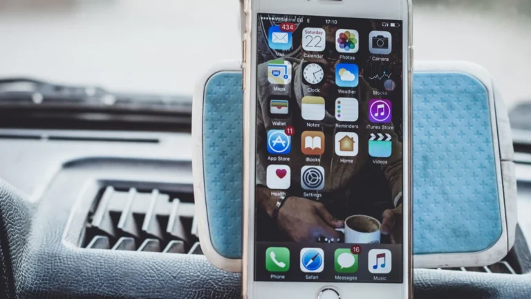 Close-up of a smartphone mounted on a car dashboard showing home screen with apps.