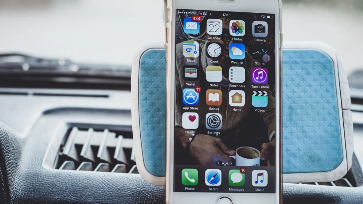 Close-up of a smartphone mounted on a car dashboard showing home screen with apps.